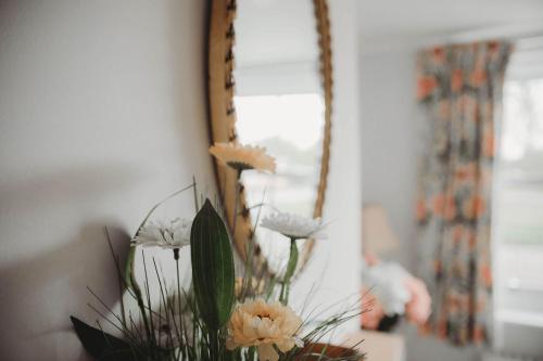 a vase with flowers in front of a mirror at Hazel's in Leiston