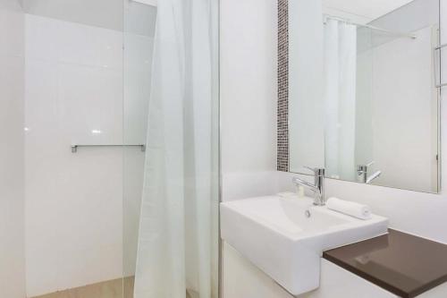 a white bathroom with a sink and a mirror at Astra Apartments Perth - Zenith in Perth