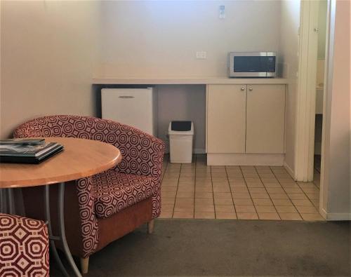 a room with a chair and a table and a microwave at Higgins Lane Motel in Margaret River Town