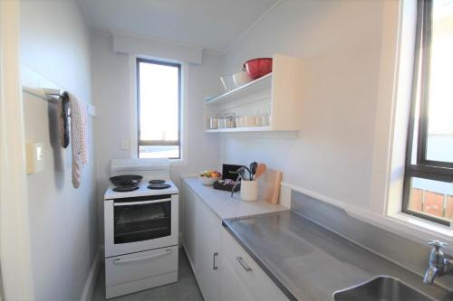 a white kitchen with a stove and a sink at Beach Lodge Motels in Dunedin