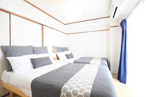 een slaapkamer met 2 bedden voor een raam bij Reisen Apartment 603 in Fukuoka
