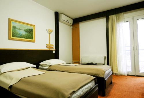 a hotel room with three beds and a window at Pensiunea Delta Dunarii in Tulcea