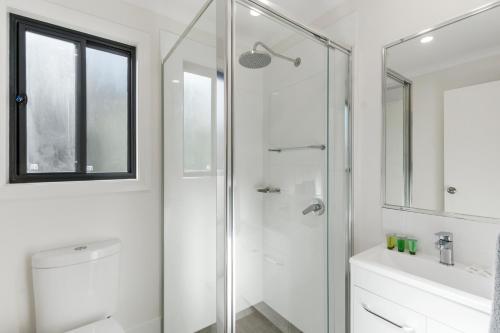 a white bathroom with a shower and a sink at Mittagong Caravan Park in Mittagong