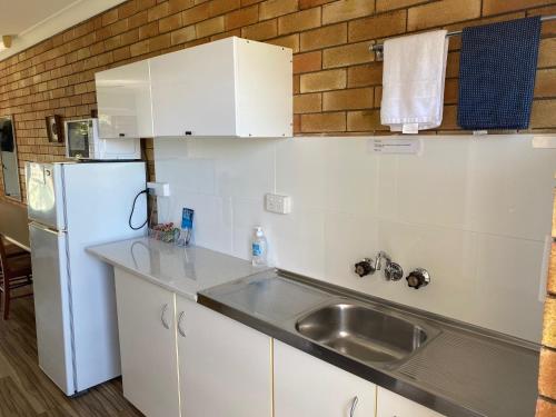 a kitchen with white cabinets and white appliances at Shelly Beach Motel in Hervey Bay