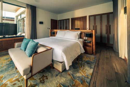 a bedroom with a large bed and a chair at Mövenpick Villas & Residences Phu Quoc in Phu Quoc