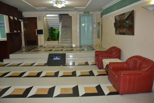 a lobby with two red chairs and a checkerboard floor at Maicao Internacional in Maicao