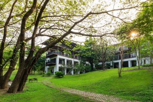 a building in the middle of a park at Rain Tree Khao Yai Hotel in Phayayen