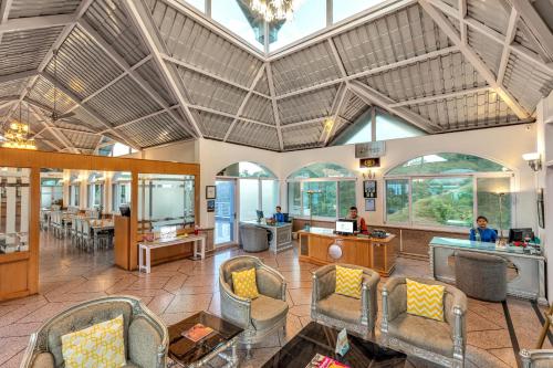 a large lobby with chairs and tables and windows at Club Mahindra Kandaghat in Kandāghāt