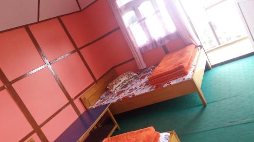 a small bed in a red room with a window at VAMOOSE ALISHA SILKROUTE in Pedong