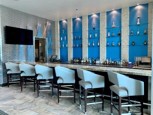 a bar with white chairs and a blue wall at Hotel Indigo Waco by IHG in Waco
