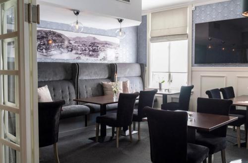 a restaurant with tables and chairs and a couch at Grand Hotel Flekkefjord in Flekkefjord