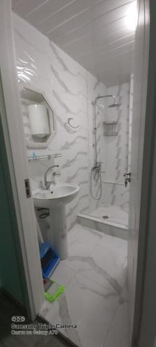 a white bathroom with a sink and a shower at Студия Радуга у моря Колхида in Batumi