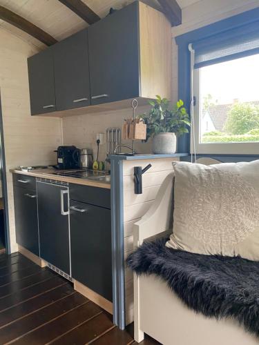 uma cozinha com armários pretos e um sofá num quarto em Pipowagen Mammaloe em Wijhe