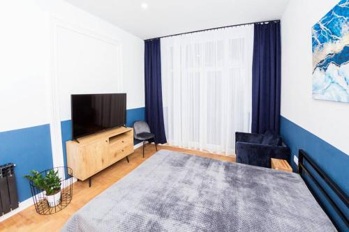 ein Wohnzimmer mit einem Bett und einem Fernseher in der Unterkunft Niebieski apartament Teatralna in Kattowitz
