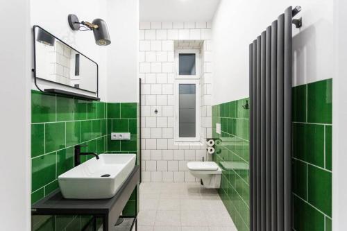 a green and white bathroom with a sink and a toilet at Niebieski apartament Teatralna in Katowice