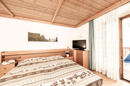 a bedroom with a large bed and a television at Bergfrieden Apartment 2 B in Siusi