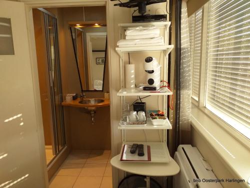 a bathroom with a shelf with towels and a sink at Bed and Breakfast Oosterpark in Harlingen