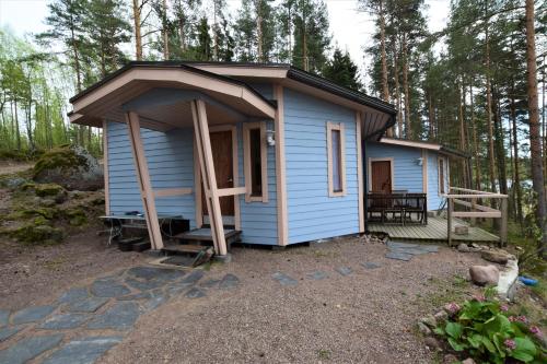 a blue tiny house in the middle of a forest at Pyhtään Vuokramökit in Tuuski