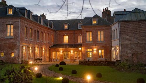 a large brick building with lights in the yard at les Myrrhophores et Spa, Chambres d'Hôtes et Gîtes de charme in Abbeville
