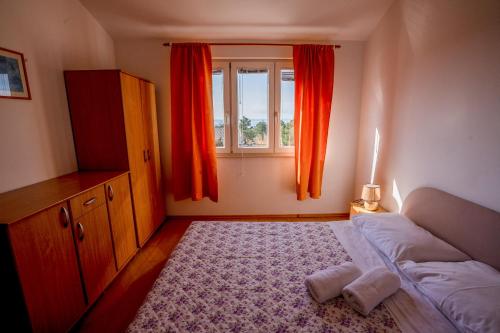 a bedroom with a bed and a window with orange curtains at Apartments Valentin in Privlaka