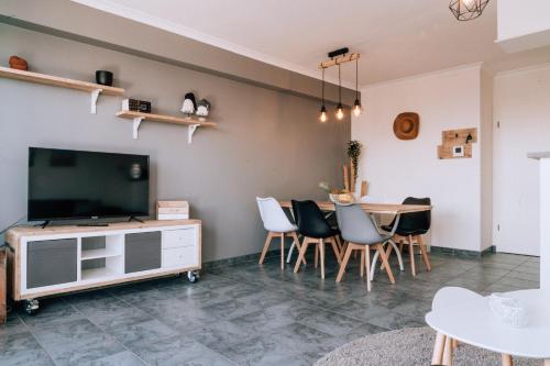 een woonkamer met een tv en een tafel en stoelen bij Casa MaTi in Blankenberge