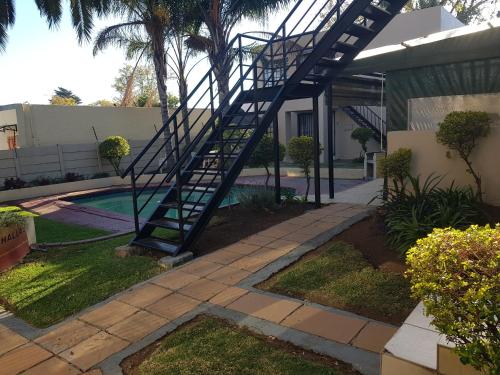 a spiral staircase leading to a house with a pool at Louhallas Accommodation in Edenvale