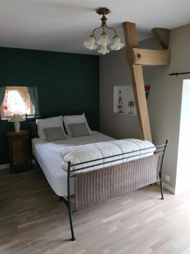 uma cama num quarto com uma parede verde em La maison à Jean em Val Couesnon
