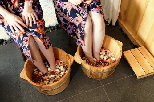 two women sitting in wooden bowls with their legs in food at Camellia Luxury Hotel Tam Đảo in Tam Ðảo