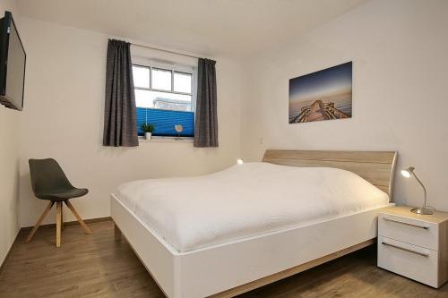 a bedroom with a white bed and a chair at Reethaus Am Mariannenweg 04a in Boltenhagen