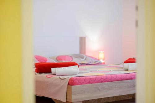 Schlafzimmer mit einem Bett mit roten und rosa Kissen in der Unterkunft Urban City Center in Šibenik