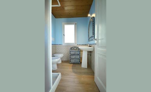 bagno con pareti blu, servizi igienici e lavandino di B&B Il Cenerino a SantʼAntìoco