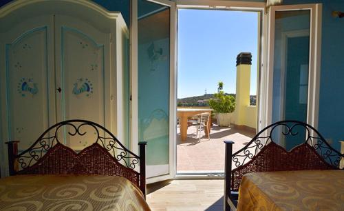 a bedroom with two beds and a sliding glass door at B&B Il Cenerino in SantʼAntìoco