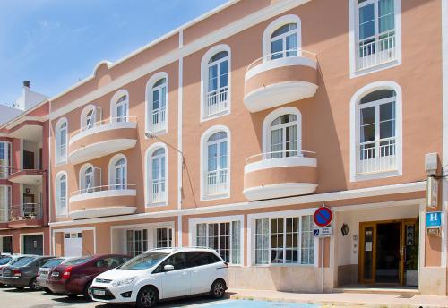 a car parked in front of a white building at Hotel Geminis in Ciutadella