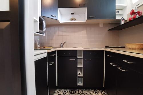 eine Küche mit schwarzen Schränken und einem Waschbecken in der Unterkunft Appartement cosy Roscoff 50 m plage thalasso WIFI PARKING in Roscoff