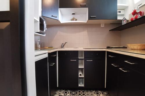 a kitchen with black cabinets and a sink at Appartement cosy Roscoff 50 m plage thalasso WIFI PARKING in Roscoff