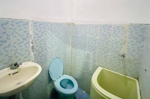 a bathroom with a blue toilet and a sink at Kanca Homestay Mitra RedDoorz near GOR Untung Suropati in Krampijangan