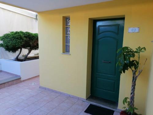 a green door on a yellow wall with a plant at Le Palme Holidays in Palmadula