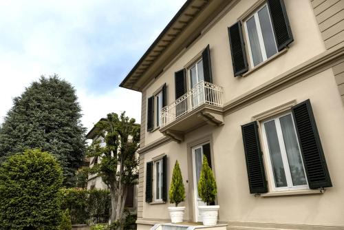 a house with black shuttered windows and a balcony at Villa La Tuia B&B in Lucca