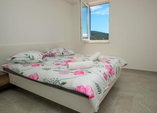een slaapkamer met een bed met roze bloemen en een raam bij Best Island View in Cres
