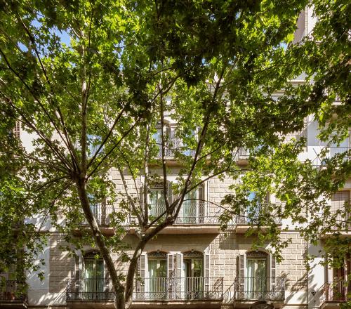 an apartment building with a balcony and trees at Casa Elliot Hotel in Barcelona