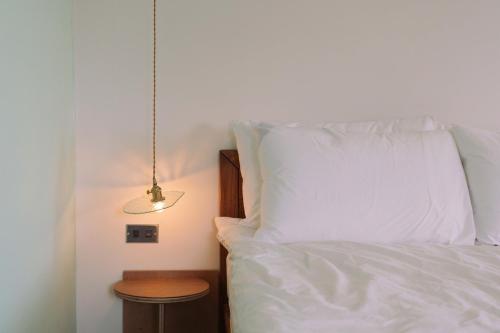a bed with a white pillow and a table at OwlStay Jiufen Green Ray - 故事所 山中夢遊 九份綠光 in Jiufen