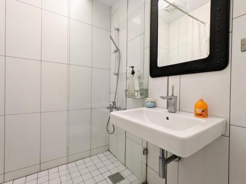 a white bathroom with a sink and a mirror at Chanmou-Chair in Tainan