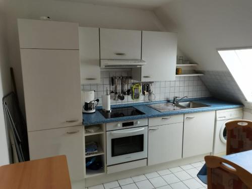 cocina con armarios blancos y encimera azul en Kleine Krabbe, en Büsum
