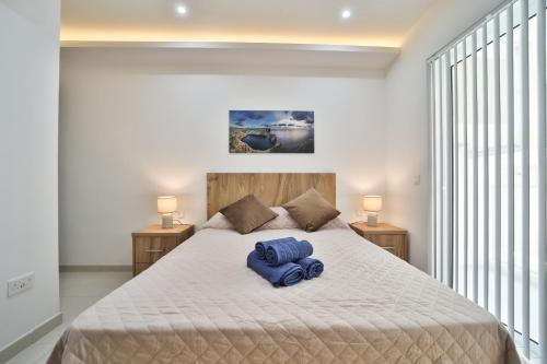 1 dormitorio con 1 cama grande y toallas azules. en Apartment 5 Ashville Court en Marsalforn