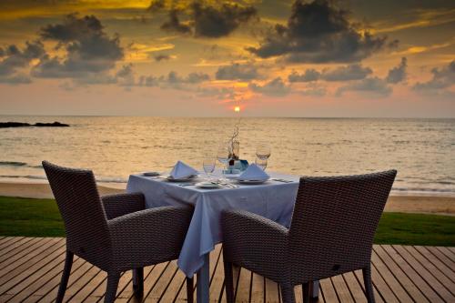 a table with wine glasses on a beach with the ocean at The Sands Khao Lak by Katathani - SHA Extra Plus in Khao Lak