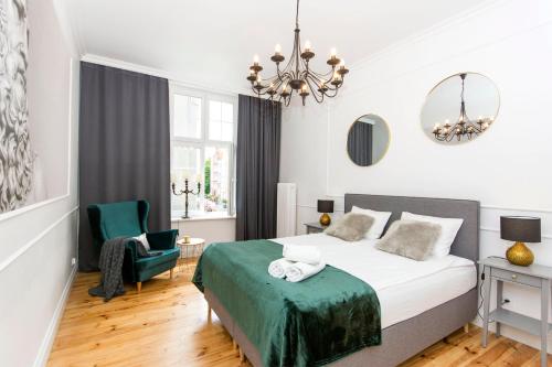 - une chambre avec un lit, une chaise et un lustre dans l'établissement Apartament na Gdańskiej Starówce, à Gdańsk