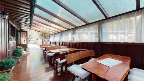 a restaurant with wooden tables and benches and windows at Penzion Sabina in Vernár