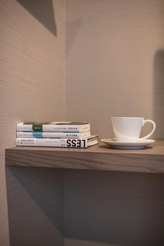 a stack of books and a coffee cup on a shelf at hotel aima in Tokyo