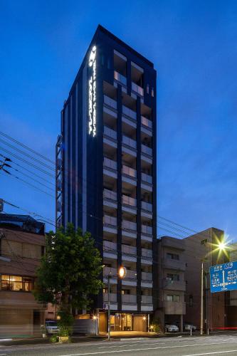a tall black building on a city street at night at HOTEL SUITE HIROSHIMA HAKUSHIMA in Hiroshima