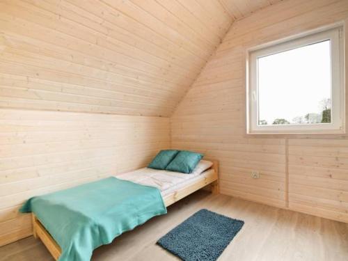 ein kleines Bett in einem Holzzimmer mit Fenster in der Unterkunft Domki Turkusowe Zacisze in Sarbinowo